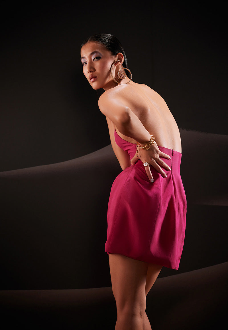 Embody an unapologetic spirit of celebration in this sculptural sleeveless dress in hot pink. Cut from lush taffeta, the dress features a sleak and clean neckline falling perfectly on the bust that is combined with a structured boned skirt offering a timeless experience. The dress is completed with a bare back and a concealed zipper. 