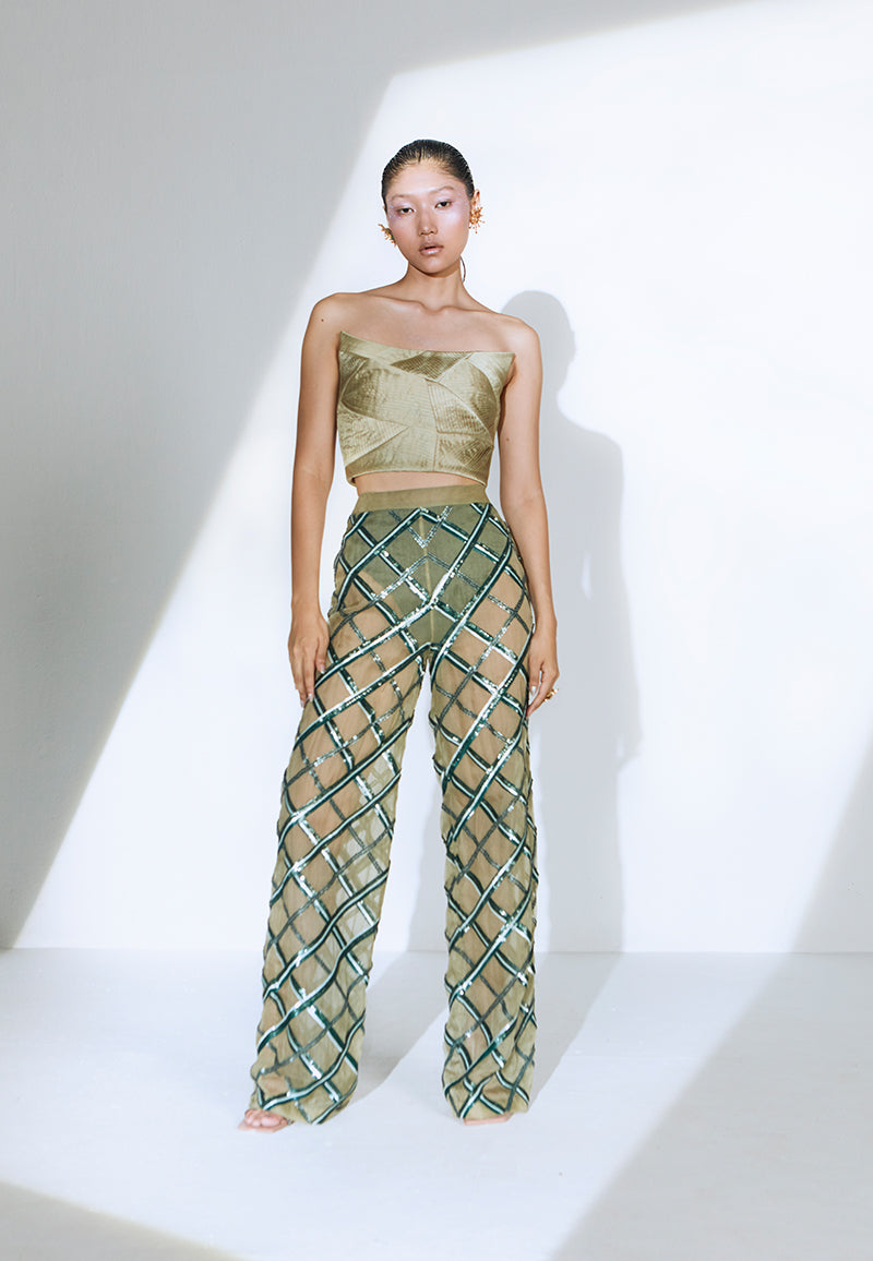 Hand-embroidered on pastel olive green net, the sheer pant features criss-cross embroidery pattern playing with different sequin sizes and colors in green. This transparent pant fall straight to floor from the high-waist. It has a zip closure at center back and comes with a pair of green underpants. Wear it for a fancy dinner party with heeled sandals or pumps and a bustier or corset to complete the look.