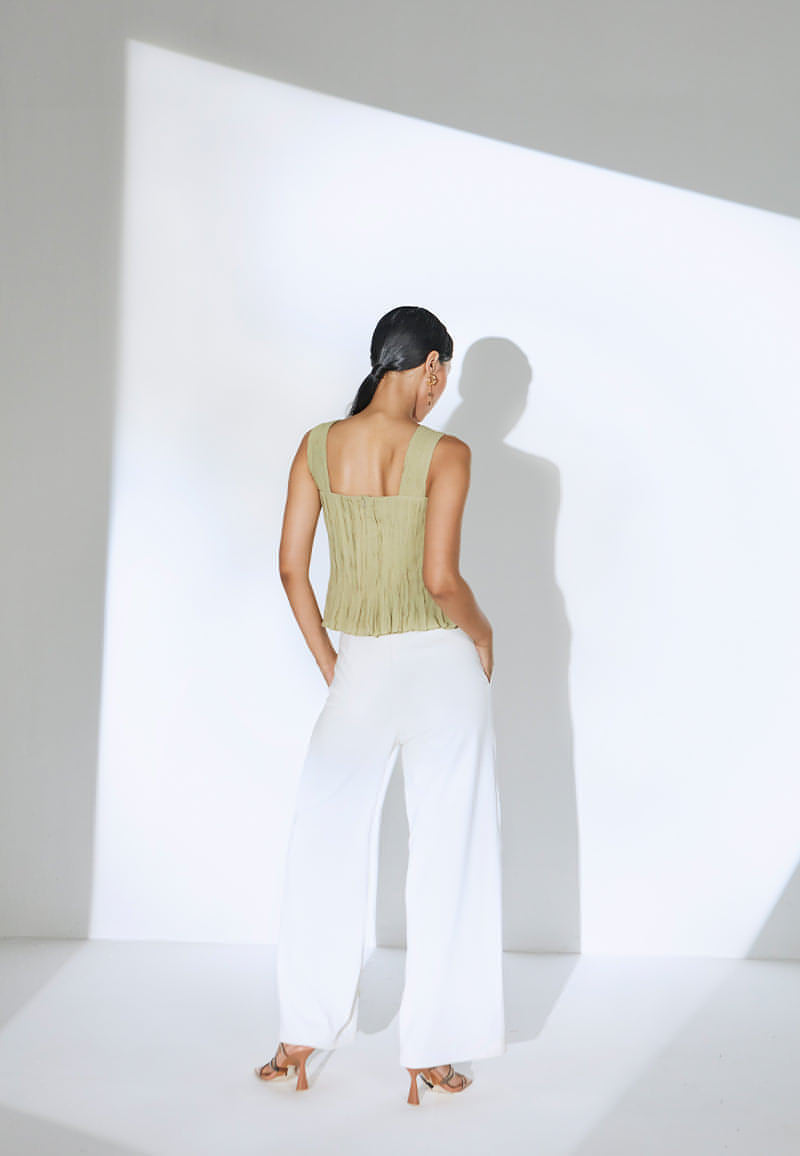 These timeless pants are made with white lycra crepe for extra comfort. The pants fall straight from the high-waist with a tie-up detail on the ankle to create another silhouette. Tie it up or leave it open depending on your mood and taste. The pant comes with inseam pockets and has a zip closure at the center back. Wear yours with a flirty top and heeled sandals or booties with minimal gold jewelry to complete the look.