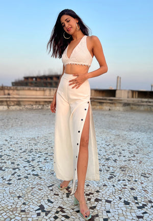 Add a dose of glamour with these high-waisted pants in white. This thigh-high slit flared pants with black buttons can be worn for different occasions. 