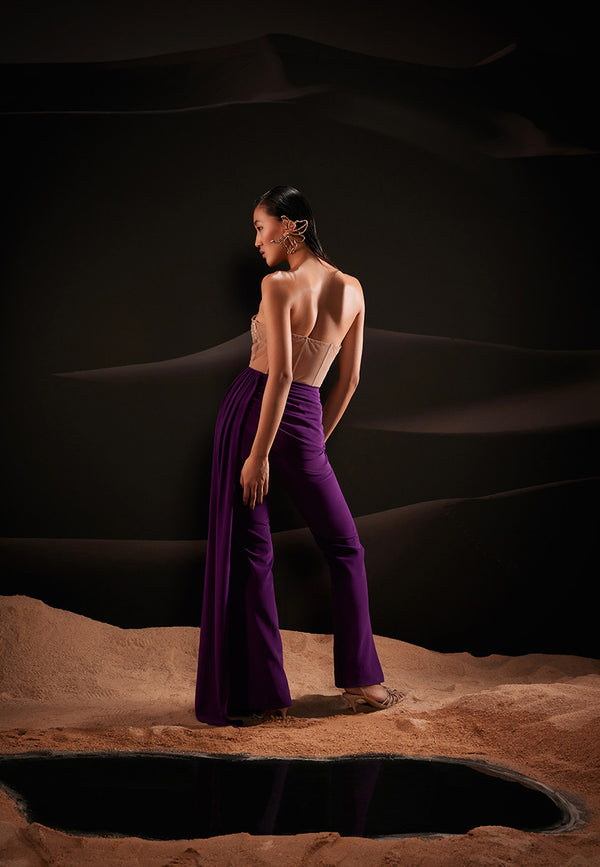 Designed using nude-coloured sequins and crepe fabric in purple hue, this corset jumpsuit features special MANNAT GUPTA details. This ensemble features a sweetheart embellished net corset in beige and attached straight pants with draped pleated trail on one side. An alluring piece perfect for a date night. Pair this attire with stelletoes and gold accessories for a tantalizing look. 