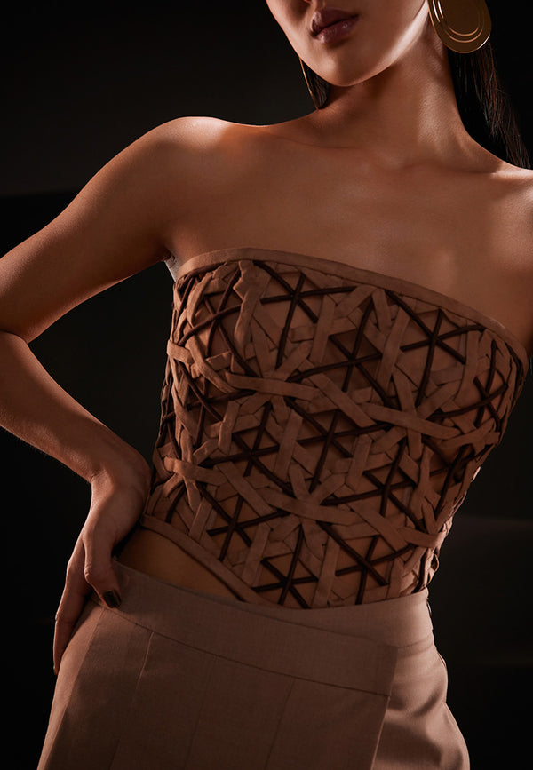 Strapless bodice top combining the classic sophistication of bustier inspired seams and form-fitting top stitching finish this exquisite geometric weaved corset in shades of brown. The suede semi-sheer top features a bandeau neckline and is crafted entirely in a diamond weave pattern. More structure has been added with the help of boning on the front and back. Pair this stunning piece with high waist faux leather pants and pumps to stimulate the overall appearance.