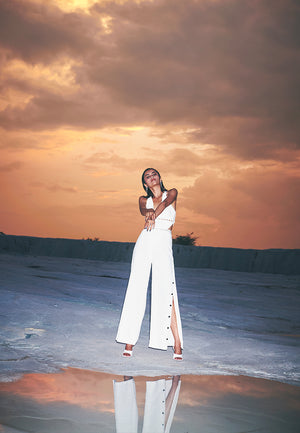 Add a dose of glamour with these high-waisted pants in white. This thigh-high slit flared pants with black buttons can be worn for different occasions. Crafted in pure white silk crepe with black buttons as closure on both sides and a concealed zip make i