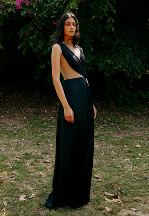 Woman's maxi dress crafted from black satin crepe fabric is a must-have for the evenings. This sleeveless floor-length gown features delicately draped ruching and pleating details with a sheer back made out of net. Style it with minimal gold jewelry and h