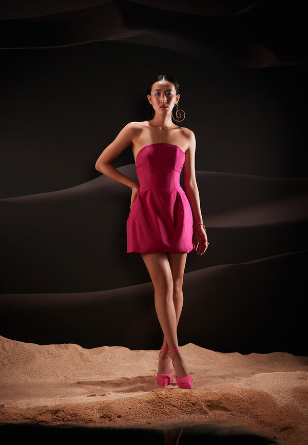 Embody an unapologetic spirit of celebration in this sculptural sleeveless dress in hot pink. Cut from lush taffeta, the dress features a sleak and clean neckline falling perfectly on the bust that is combined with a structured boned skirt offering a timeless experience. The dress is completed with a bare back and a concealed zipper. 