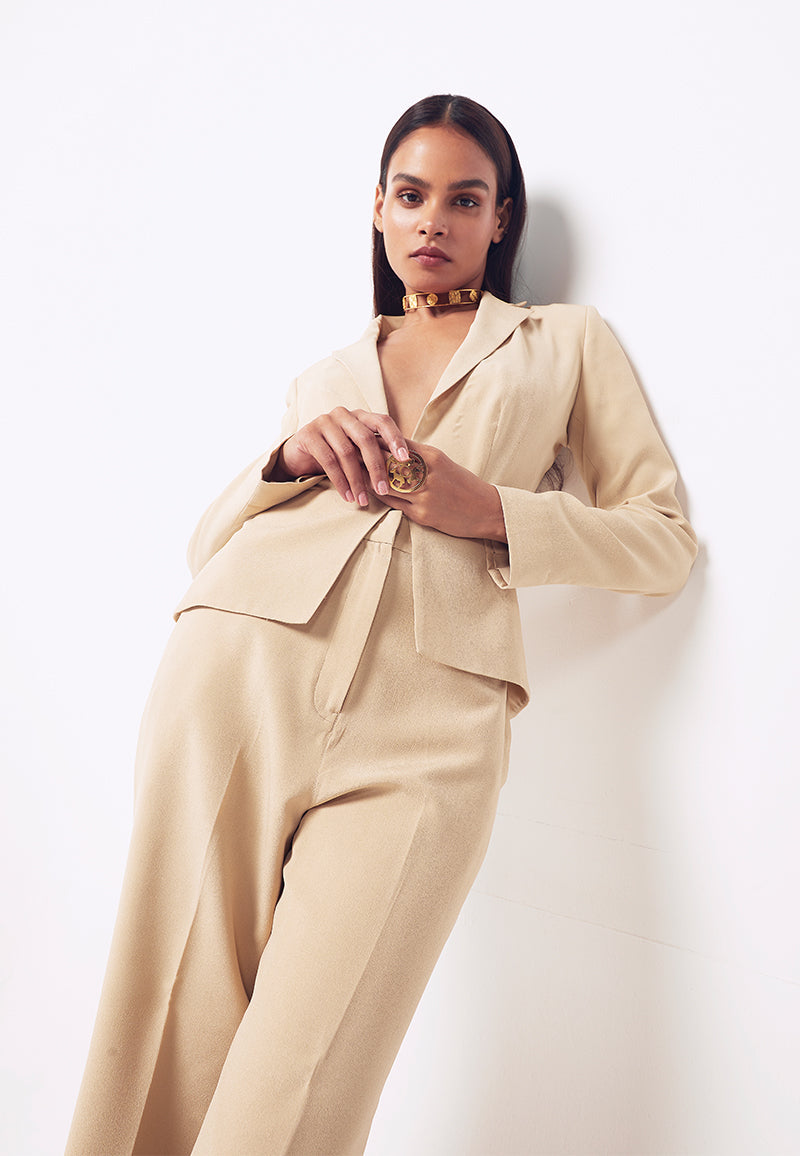 This beige peplum-inspired silk crepe jacket and pant co-ord set features asymmetrical pleat detail on the back with hidden hook and eye closure in the center front. This military gold power suit comes with high-waisted flared crepe pants in the same colour with inseam pockets on both sides. Style this elegant ensemble in summers with heeled sandals for your next meeting or formal dinner or layer it with a wool coat or jacket in winters. Pair it with minimal gold jewelry for an elevated and elegant look.