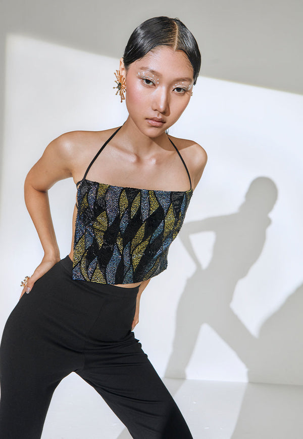 Hand-embroidered with yellow, blue, and black sequins this backless halter-neck square cropped top features tie-up details around the neck and the bust. Pair this flared pants or a mini skirt and heeled sandals to complete the look. 