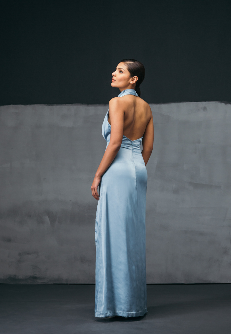 Mannat Gupta’s mini and maxi dresses collection. Shine like a star with our icy blue maxi dress. This turquoise color will add more value to your party look. Made  with glossy silk satin with an alluring cowl neckline and an undulating high-slit cut that tumbles gracefully to a floor-pooling hem.This dress heightens the modern elegance of maxi dress. You can wear this maxi dress at a glamorous dinner or for a cocktail party.  Pair with high heels or sandals and some diamonds to complete the look.