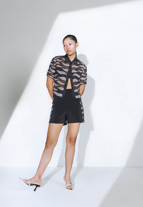 This sheer sequin shirt is embellished with transparent, flush pink sequins and features a soft collar. A ready-to-party shirt constructed using black organza with concealed buttons on the center front. The shirt comes with a pair of high-waisted black shorts that are cut and constructed in crepe. The side seams of the shorts are patched with sequin embroidery on organza with a concealed zip closure at the center back. This co-ord set is the perfect mood setter for a lavish boat party or your next dinner. 