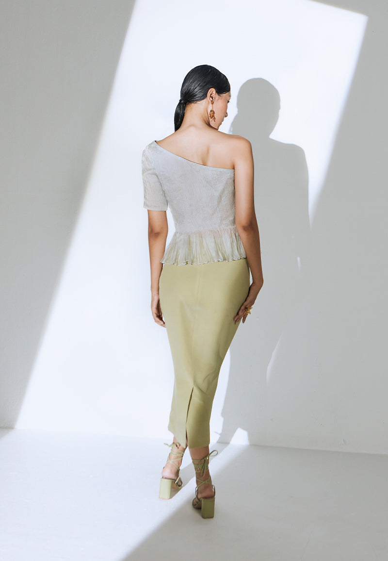 Make a statement with this simple yet classy pastel olive green midi skirt constructed in crepe. This high-waisted skirt has a bodycon fit and is mid-calf in length. It features a zip closure at the center back with a flap opening at the bottom for free movement. A versatile and minimal piece that can be paired with any of our bodysuits, corsets or bustiers. Pair yours with minimal gold jewelry and heeled sandals to complete the look. 