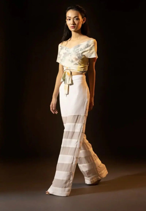 Women’s high-waisted straight pants panelled with silk crepe and chiffon in white; the perfect pair of pants to deal with the summer’s heat. Complete the look with a printed crop top and heeled sandals.