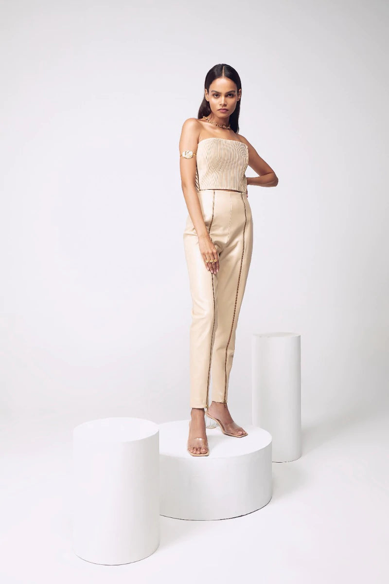 Versatile and minimal crop top collection from Mannat Gupta which every woman will love to have. You can style in this beautiful gold corseted crop top which is made using artificial leather. The beige bandeau crop top is hand-pleated all around which adds a beautiful texture. The top comes with gold metal zippers on both sides for a detachable element. Pair this crop top with leather shorts or trousers, minimal gold jewelry and high sandals for your next night out.