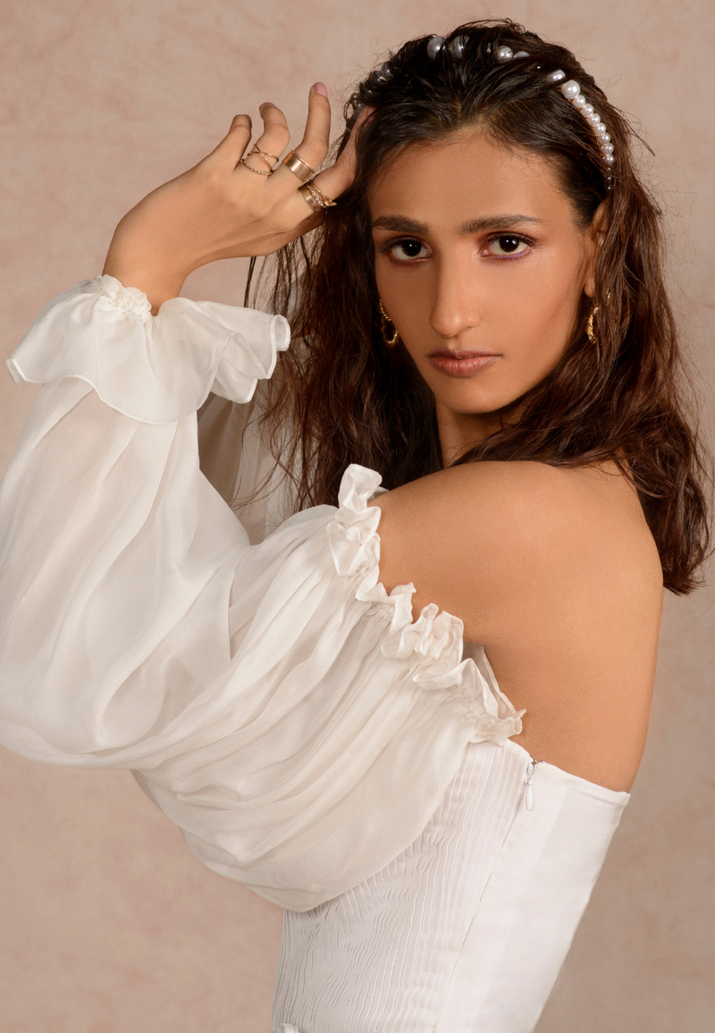 Women’s contemporary white pleated bodysuit with close, figure-hugging fit. The puffed sleeve made in chiffon adds extra volume to the ensemble. This off-shoulder piece with a hidden zipper on the side can be paired with pants, skirts, or shorts. Slip in this beautiful bodysuit in summers for high fashion and be the game-changer.