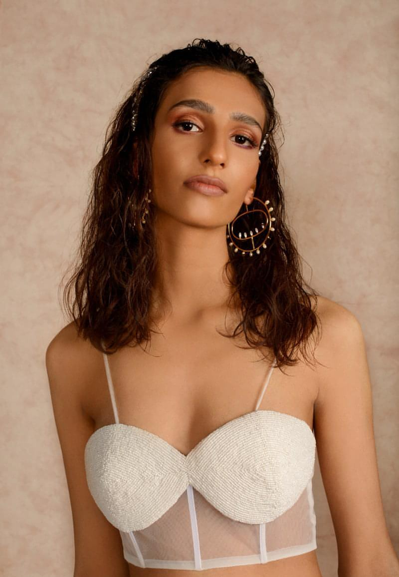 Women’s beautiful beaded bustier top in white. This sleeveless handcrafted bandeau is made from net and crepe. Style it in multiple ways for any season and create a new look every time. Wear the piece as is in the summers for a girl's night out or brunch with a leather skirt or skorts or layer the piece with a leather jacket or wool coat for the winters for your next date.